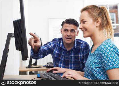 Businessman Giving Computer Training To Female Trainee In Office