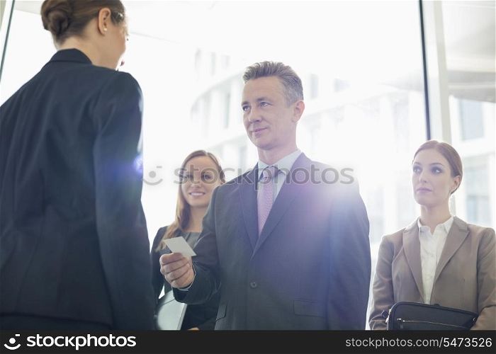Businessman giving his card to female coworker in office