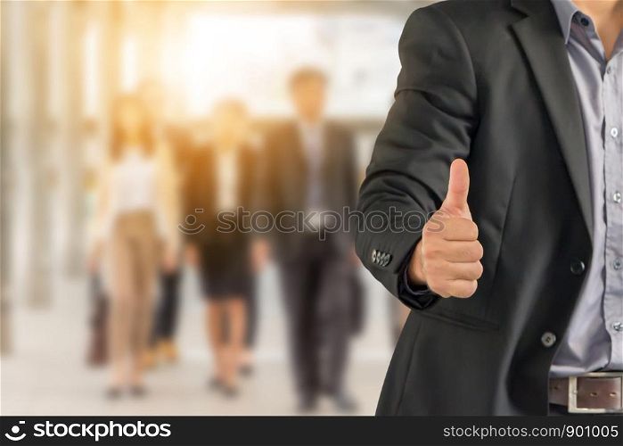 Businessman giving thumb up as sign of Success over blurred business people team background