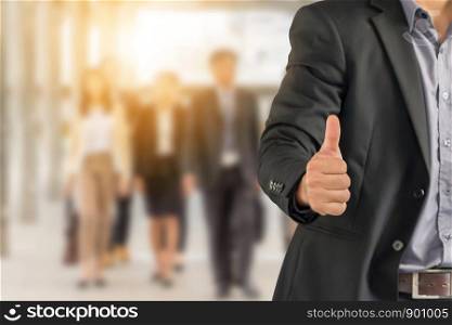 Businessman giving thumb up as sign of Success over blurred business people team background