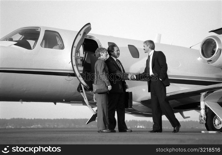 Businessman Greeting Man And Woman Getting Off Plane
