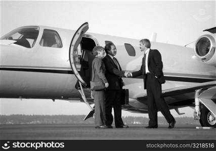 Businessman Greeting Man And Woman Getting Off Plane