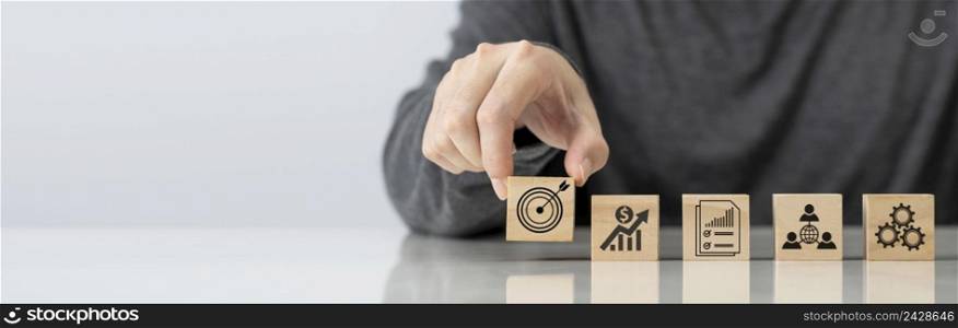 Businessman hand arranging wood block with business goal symbol ideas , Planning for goals against business success , Business strategy and marketing target concept