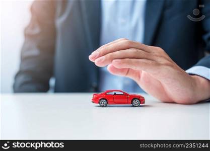 Businessman hand cover or protection red car toy on table. Car insurance, warranty, repair, Financial, banking and money concept