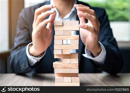 Businessman hand cover wooden block on the tower. Business planning, Risk Management, Solution and strategy Concepts