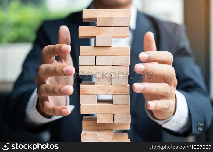 Businessman hand cover wooden block on the tower. Business planning, Risk Management, Solution and strategy Concepts