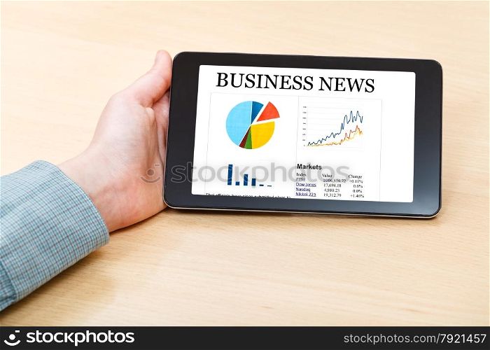 businessman hand hold tablet PC with business news on screen at office desk