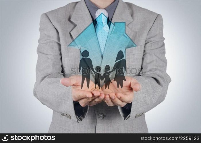 businessman hand holding 3d house with family icon as insurance concept