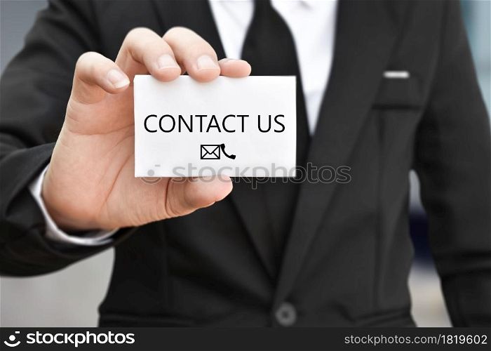 Businessman hand holding business card with the message contact us. Idea for customer support hotline people connect