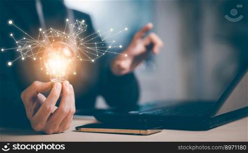 Businessman hand holding light bulb with icons and working on the desk, Creativity and innovation are keys to success.Concept of new idea and innovation with energy and power , working at home,