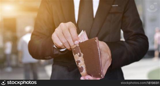 Businessman hand holding open leather wallet with cash. business and finances concept.
