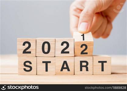 Businessman hand holding wooden cube and flip over block 2021 to 2022 START on table background. Resolution, plan, review, change ,goal and New Year holiday concepts