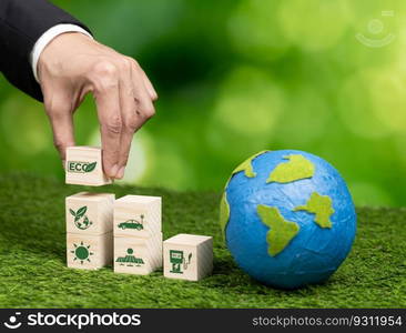 Businessman hand holding wooden cube with eco symbol and paper globe on fertile soil background. Environmental awareness and sustainable energy. Clean and renewable energy for greener ecology. Alter. Wooden cube with eco symbol and paper globe on fertile soil background. Alter