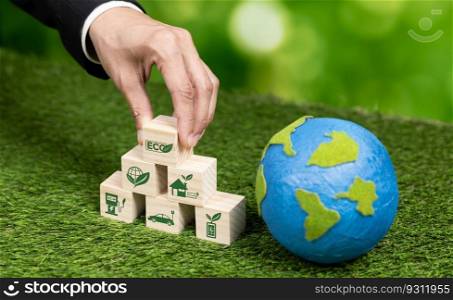 Businessman hand holding wooden cube with eco symbol and paper globe on fertile soil background. Environmental awareness and sustainable energy. Clean and renewable energy for greener ecology. Alter. Wooden cube with eco symbol and paper globe on fertile soil background. Alter