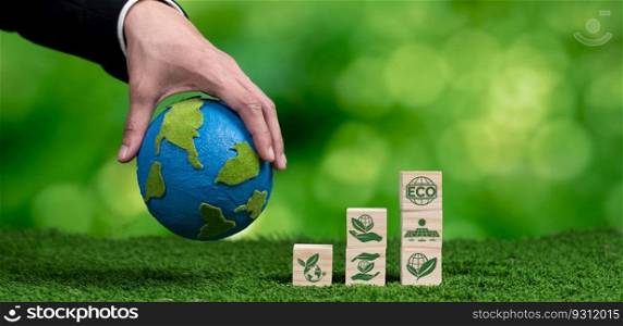 Businessman hand holding wooden cube with eco symbol and paper globe on fertile soil background. Environmental awareness and sustainable energy. Clean and renewable energy for greener ecology. Alter. Wooden cube with eco symbol and paper globe on fertile soil background. Alter