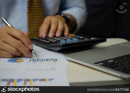 businessman hand pen with graphs and charts business documents calculator and computer laptop.Financial and tax marketing business concept.