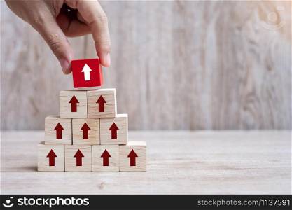 Businessman hand placing or pulling Red arrow wooden block on table background. Business Growth, Improvement, strategy and Successful Concepts