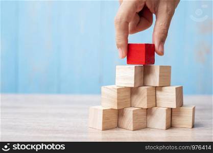 Businessman hand placing or pulling Red wooden block on the building. Business planning, Risk Management, Solution, strategy, different and Unique Concepts