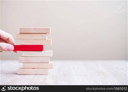 Businessman hand placing or pulling red wooden block on the tower. Business planning, risk Management, Solution, Resolving and strategy Concepts