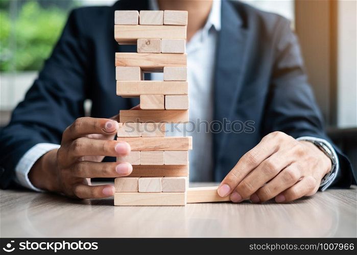 Businessman hand placing or pulling wooden block on the tower. Business planning, Risk Management, Solution and strategy Concepts