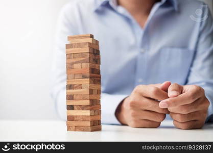 Businessman hand placing or pulling wooden block on the tower. Business planning, Risk Management, Solution and strategy Concepts