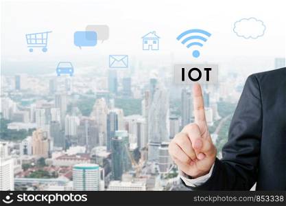 Businessman hand pointing the internet of things button over icons and blur city scrape background, business and technology concept