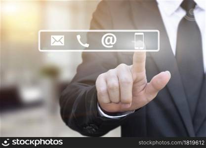 Businessman hand pressing a contact us icons on blur office lights background.