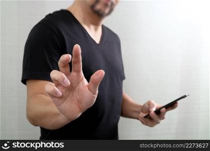 Businessman hand pressing an imaginary button,holding smart phone,digital screen graphic virtual icons,graph,diagram