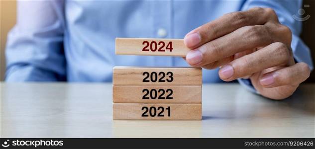 Businessman hand pulling 2024 wooden building blocks on table background. Business planning, Risk Management, Resolution, strategy, solution, goal, New Year New You and happy holiday concepts