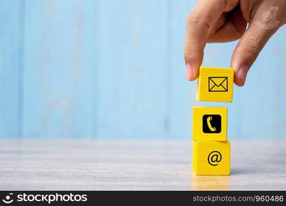 Businessman hand putting wooden block cube symbol email, telephone and address website. contact, marketing and information concept