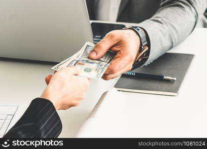 Businessman hand sending money to another business person. Transaction, payment, salary and banking concept.