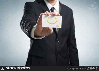 Businessman hand showing business card with smile icon .Concept of happy and satisfaction customer experience .