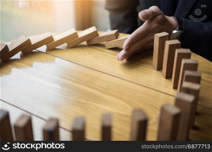 businessman hand stop dominoes continuous toppled or risk with copyspace