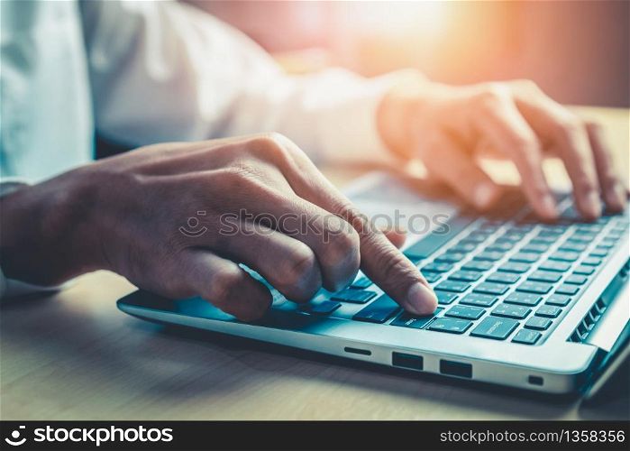 Businessman hand typing on computer keyboard of a laptop computer in office. Business and finance concept.