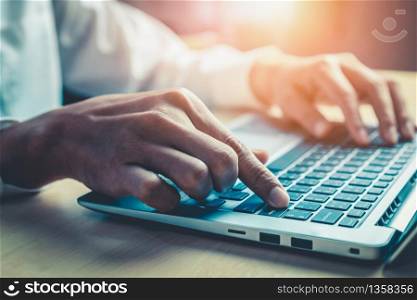 Businessman hand typing on computer keyboard of a laptop computer in office. Business and finance concept.