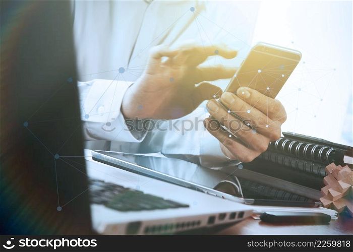 Businessman hand using laptop and mobile phone on wooden desk as concept