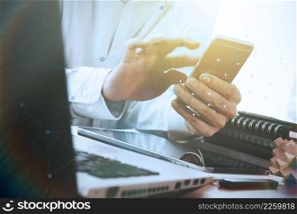 Businessman hand using laptop and mobile phone on wooden desk as concept