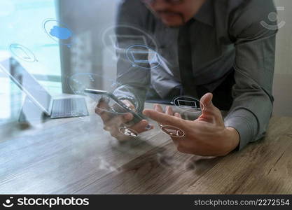 Businessman hand using mobile payments online shopping,omni channel,in modern office wooden desk,icons graphic interface screen,eyeglass