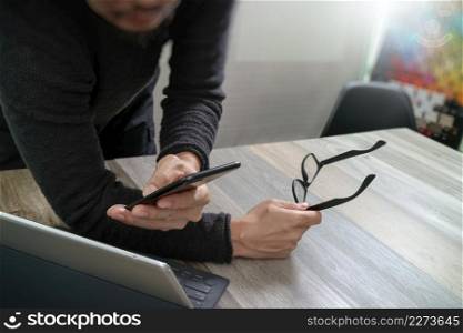 Businessman hand using mobile payments online shopping,omni channel,in modern office wooden desk,icons graphic interface screen,eyeglass