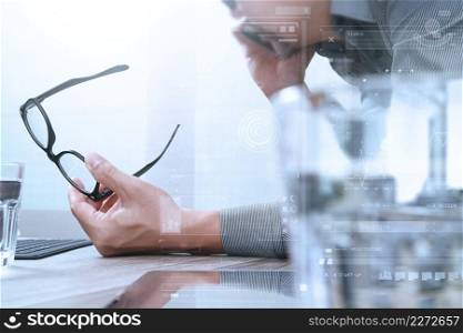 Businessman hand using mobile payments online shopping,omni channel,laptop computer on wooden desk,digital screen graphic virtual icons,graph,diagram