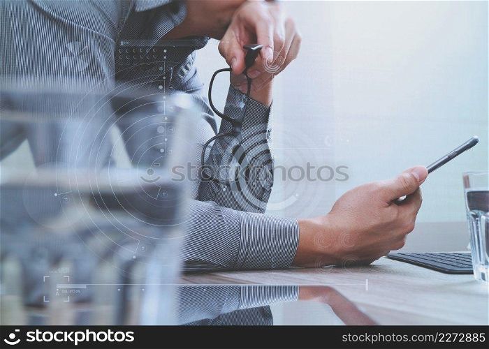 Businessman hand using mobile payments online shopping,omni channel,laptop computer on wooden desk,digital screen graphic virtual icons,graph,diagram