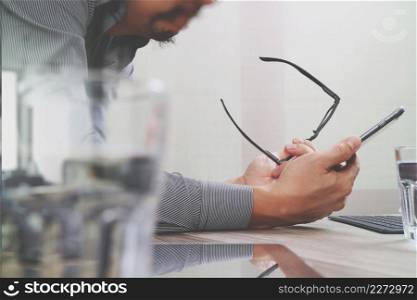 Businessman hand using mobile payments online shopping,pencil,omni channel,laptop computer on wooden desk in modern office,filter effect