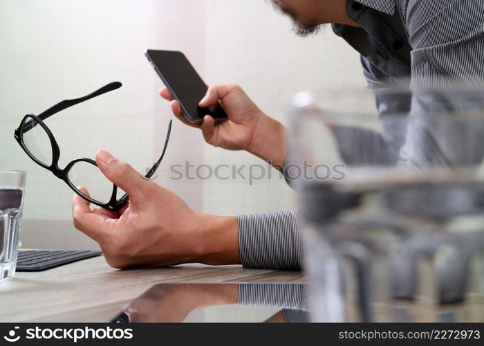 Businessman hand using mobile payments online shopping,pencil,omni channel,laptop computer on wooden desk in modern office