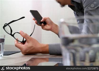 Businessman hand using mobile payments online shopping,pencil,omni channel,laptop computer on wooden desk in modern office