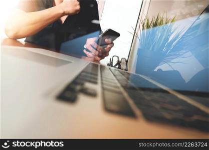 Businessman hand using mobile phone with laptop computer as business strategy concept