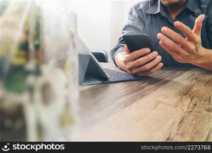 businessman hand using smart phone,mobile payments online shopping,omni channel,digital tablet docking keyboard computer,flower glass vase on wooden desk,fiter