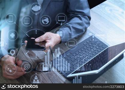businessman hand with eyeglasses using smart phone,mobile payments online shopping,omni channel,digital tablet docking keyboard computer,compact server on wooden desk,virtual interface icons screen