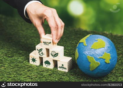 Businessman hand with paper globe and net zero symbol cube for eco awareness. Ethical company reduce CO2 emission, fight climate change and global warming by clean energy for green environment. Alter. Businessman hand with paper globe and wooden cube net zero symbol for eco. Alter