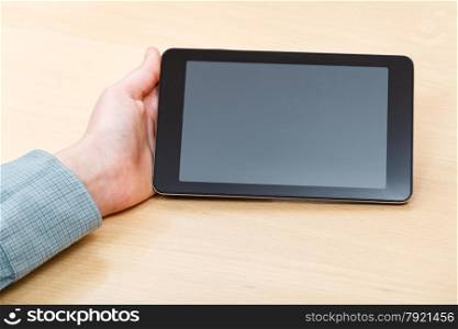 businessman hand with tablet PC with black screen at office table