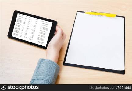 businessman hand with tablet PC with data on screen at office table